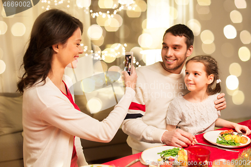 Image of happy family taking picture at christmas dinner