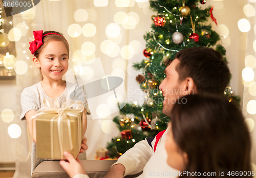 Image of happy family with christmas present at home