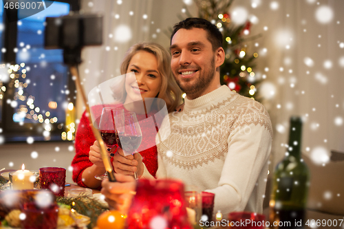 Image of couple taking picture by selfie stick at christmas