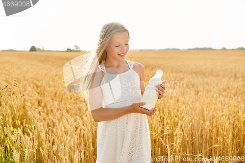 Image of happy girl with bottle of milk on cereal field