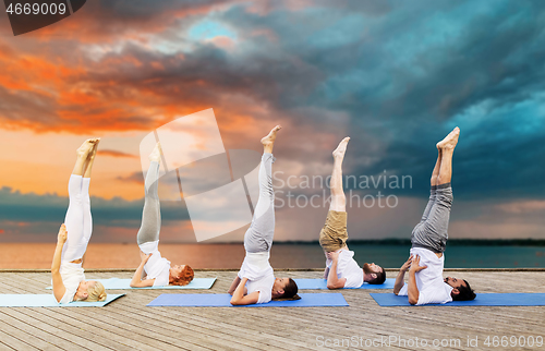 Image of people making yoga in shoulderstand pose on mat