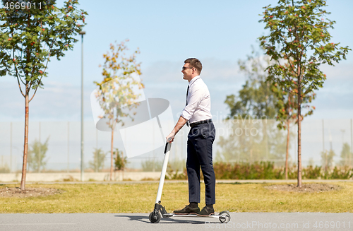 Image of young businessman riding electric scooter outdoors