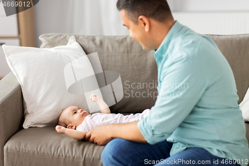 Image of middle aged father playing with baby at home