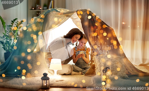 Image of happy family with smartphone in kids tent at home