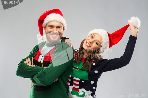 Image of happy couple in christmas sweaters and santa hats