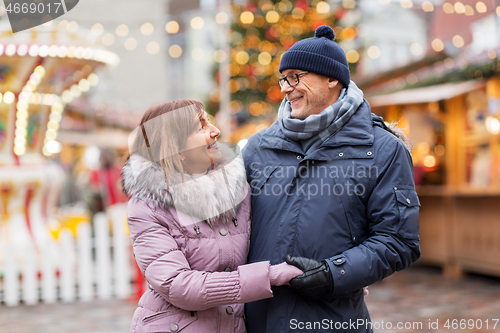 Image of happy senior couple hugging at christmas market