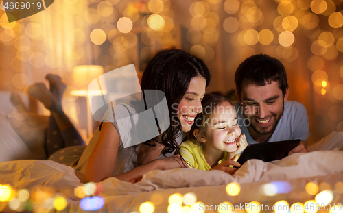 Image of family with tablet pc in bed at night at home