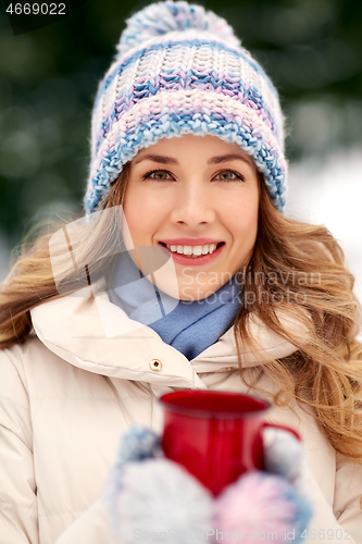 Image of happy young woman with tea cup outdoors in winter