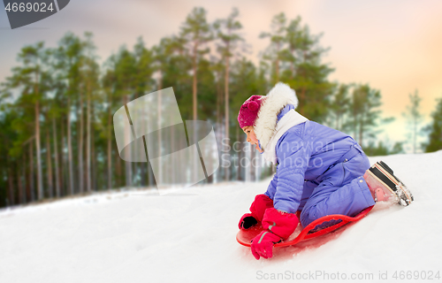 Image of girl sliding down on snow saucer sled in winter