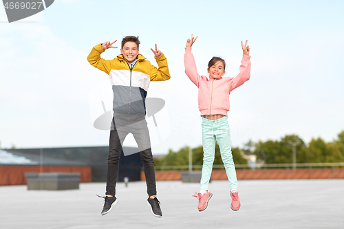 Image of happy children jumping on roof and showing peace