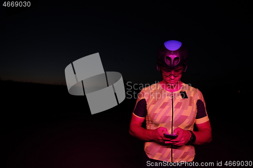 Image of athlete cyclist having a break using smart phone