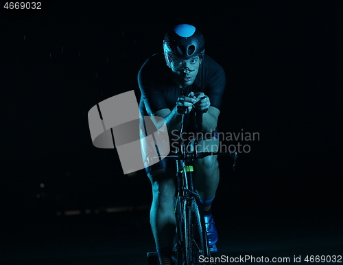 Image of triathlon athlete riding bike fast at night