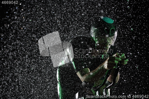 Image of triathlon athlete riding bike fast on rainy night