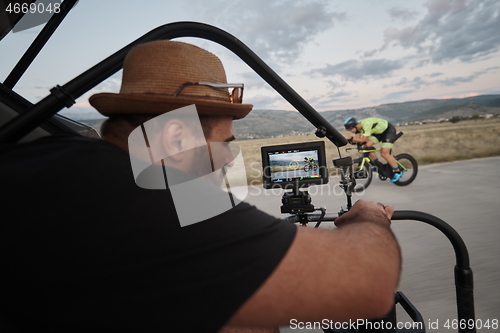 Image of videographer taking action shot of triathlon athlete while riding bike