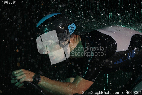 Image of triathlon athlete riding bike fast on rainy night