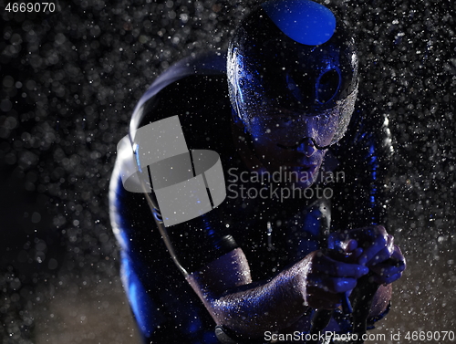 Image of triathlon athlete riding bike fast on rainy night