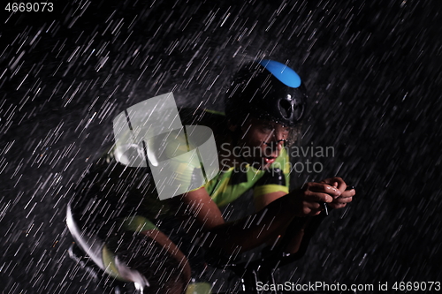 Image of triathlon athlete riding bike fast on rainy night