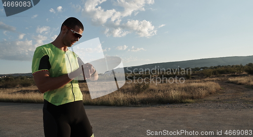 Image of triathlon athlete resting and setting smartwatch