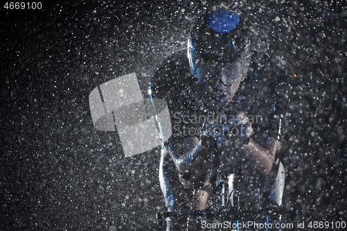 Image of triathlon athlete riding bike fast on rainy night