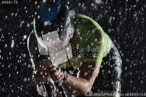 Image of triathlon athlete riding bike fast on rainy night