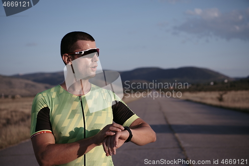 Image of triathlon athlete resting and setting smartwatch