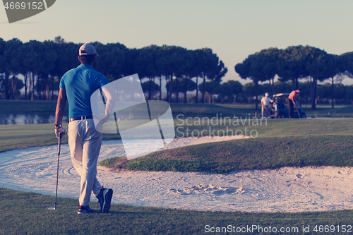 Image of golfer from back at course looking to hole in distance