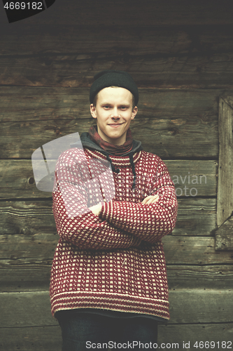 Image of young hipster in front of wooden house