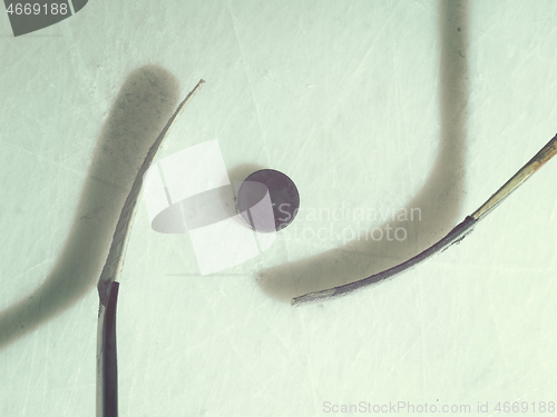 Image of hockey sticsk and puck on ice