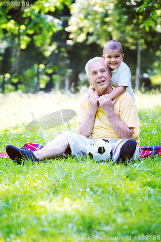 Image of grandfather and child in park using tablet