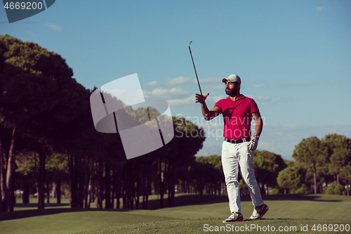 Image of golf player walking and carrying driver