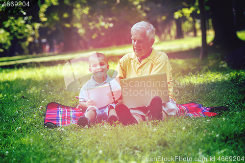 Image of grandfather and child in park using tablet