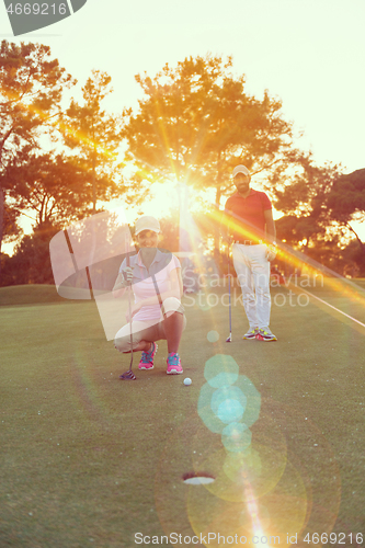 Image of couple on golf course at sunset