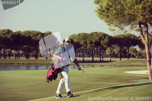 Image of golfer  walking and carrying bag