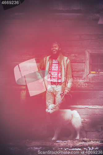 Image of hipster with dog in front of wooden house