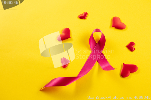 Image of the text world cancer day and a pink ribbon on a table background