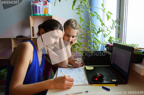 Image of tutor explains to the child how to do the job in a notebook