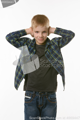 Image of Boy covers his ears with his hands on a white background in everyday clothes