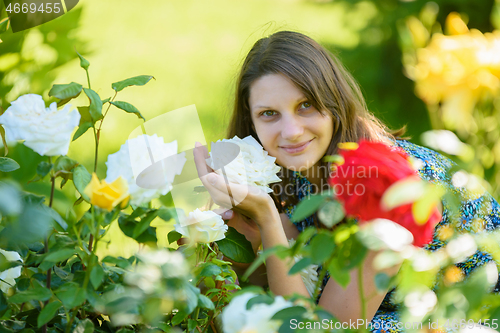 Image of portrait of a smiling girl against the backdrop of roses in the park