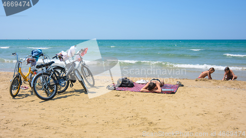 Image of On the sandy seashore, a family arriving on bicycles rests