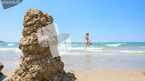 Image of A pile of wet sand on the seashore, on the right there is an empty place for inscription, in the background a girl runs