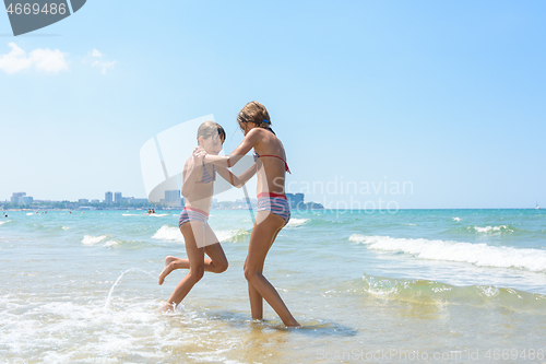 Image of Two girls joyfully play and run along the seashore