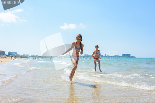 Image of Two girlfriends run along the coastal strip of the sea coast