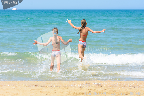 Image of Cheerful children run to swim in the sea