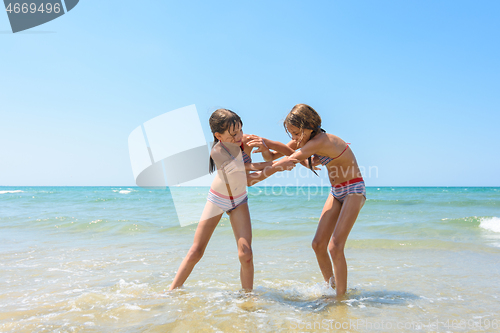 Image of Two girls fight on the sandy beach of the sea