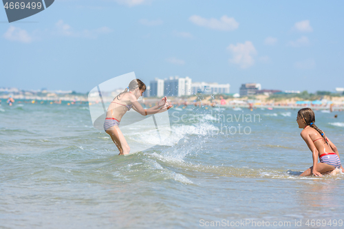 Image of Girls splashing on the seashore on a hot sunny day