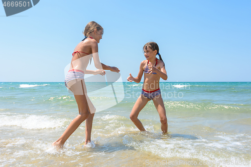 Image of Two girls playing fight on the seashore in the water