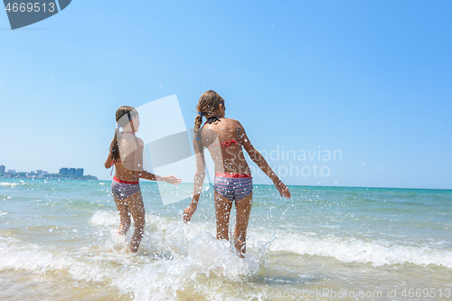 Image of Two girls went knee-deep into the water and enjoy the sea