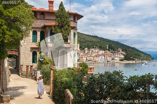 Image of Female tourist walking along Adriatic sea coast relaxing on vacation in Moscenicka Draga, Istria, Croatia.