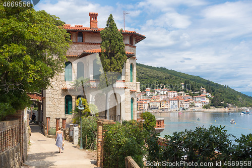 Image of Female tourist walking along Adriatic sea coast relaxing on vacation in Moscenicka Draga, Istria, Croatia.