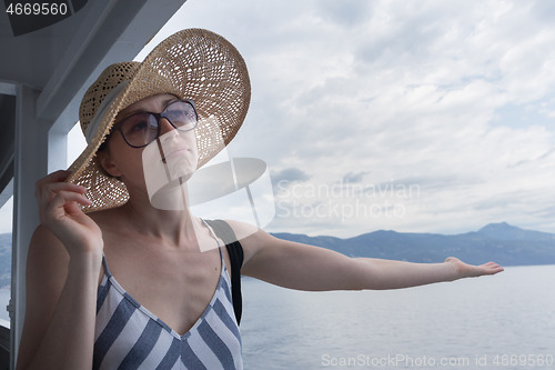 Image of Disappointed female tourist on summer cruss ship vacation, checking if it rains, looking angry at overcast cloudy sky. Allways take the weather with you on summer vacations